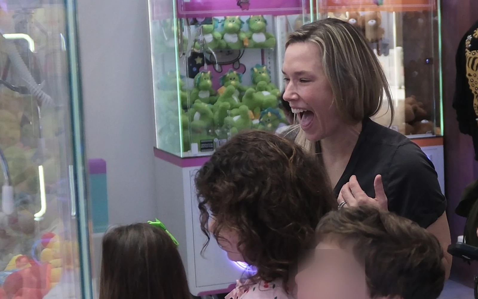 A boy looking up wide-eyed at a claw machine while his mother laughs beside him at Claw Stars