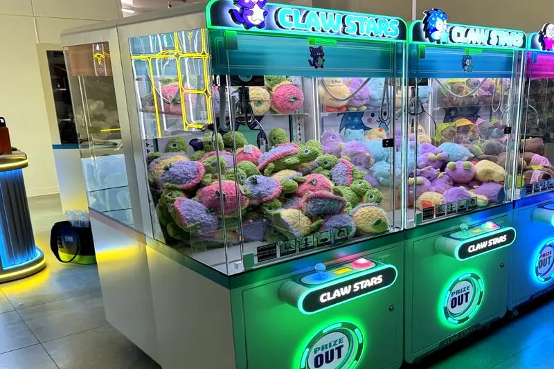 A long row of lit claw machines running down the Claw Stars floor